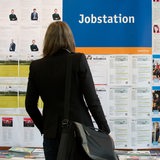Eine Frau steht vor einer Wand mit Stellenangeboten.
