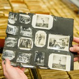 Ein Archivar hält im Archiv des DRK-Suchdienstes eine Karteikarte mit mehreren Fotos in den Händen.