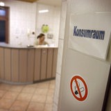 Eine offene Tür an der ein Schild mit Konsumraum steht