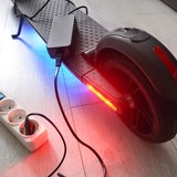 Ein E-Scooter wird an einer Steckdose aufgeladen.