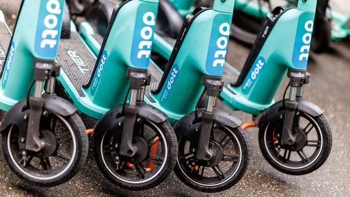 Mehrere E-Scooter der marke "Dott" stehen nebeneinander.
