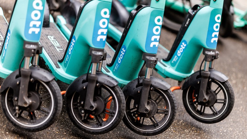 Mehrere E-Scooter der marke "Dott" stehen nebeneinander.