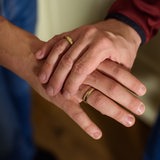 Zwei Menschen mit Eheringen an den Fingern halten Hände