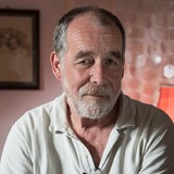 Der Regisseur und Produzent Eike Besuden sitzt in einem Raum und guckt vorsichtig lächelnd in die Kamera.