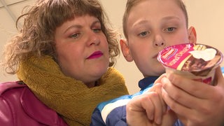 Eine Mutter hilft ihrem jungen Sohn beim einkaufen glutenfreier Produkte im Supermarkt.