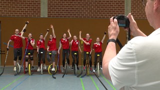 Die Lilienthaler Einradhockey-mannschaft in roten vereinstrikots auf in der Sporthalle.