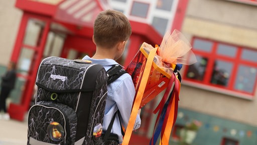 Ein Schulkind mit Ranzen und Schultüte von hinten fotografiert