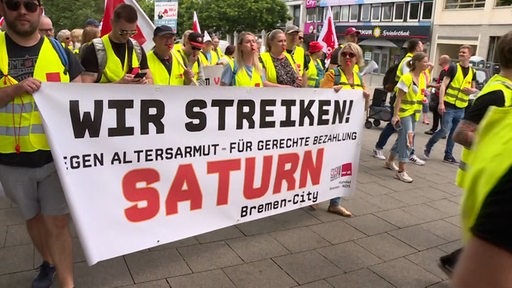 Mehrere Menschen ziehen bei einem Streik in gelben Warnwesten durch die Innenstadt von Hannover.