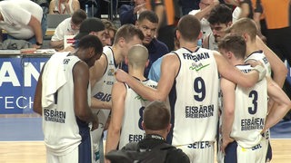 Die Basketball-Spieler der Eisbären Bremerhaven stehen in einem Kreis auf dem Spielfeld. 