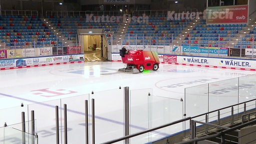 In einer Eissporthalle fährt eine Eisbearbeitungsmaschiene über das Eis.
