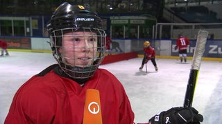 Nachwuchs-Eishockeyspielerin Annica Busch steht mit Helm auf dem Kopf beim Interview auf dem Eis.