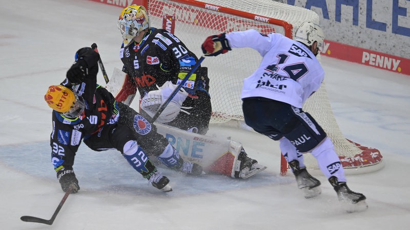 Eishockey-Spieler Nicolas Appendino von den Fischtown Pinguins rutscht heran, um das Tor gegen einen Mannheimer Spieler zu verteidigen.