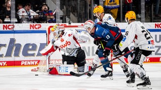 Die Eishockey-Profis der Fischtown Pinguins verteidigen mit vollen Einsatz ihr Tor gegen einen Nürnberger Spieler.