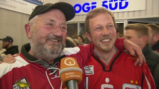 Fans der Pinguins, Vater und Sohn, liegen sich am Arm.