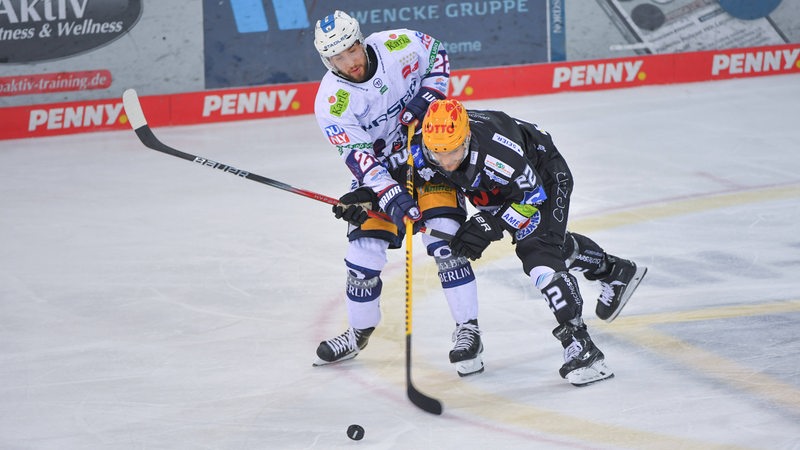 Een speler van de Fischtown Penguins en Eisbären Berlin kampeert rond de Puck.