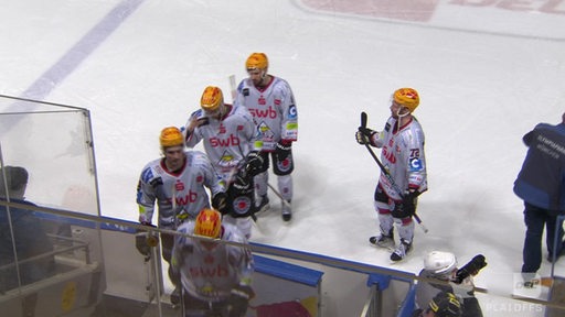 Mehrere Eishockeyspieler von den Fischtown Pinguins stehen in ihrer Ausrüstung auf Eis.
