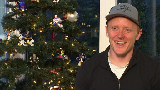 Eishockey-Profi Ross Mauermann im Interview vor einem Weihnachtsbaum.