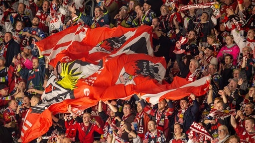 Eishockey-Fans der Fischtown Pinguins aus Bremerhaven ziehen im Jubel eine große, rote Vereinsfarbe über den Fan-Block.
