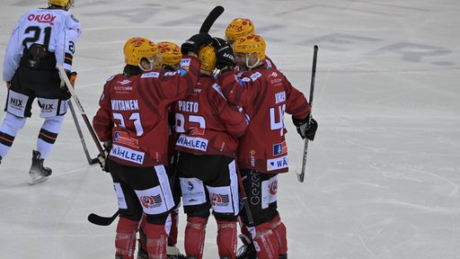 Eishockey-Spieler der Fischtown Pinguins in roten Trikots kommen nach einem Treffer zum jubeln zusammen.