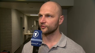 Eishockey-Manager Sebastian Furchner von den Fischtown Pinguins steht in einem Gang in der Kölner Arena beim Interview nach dem ersten Sieg in den Play-offs.