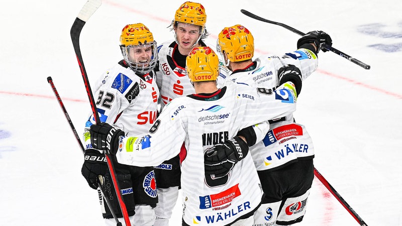 Eishockey-Spieler der Fischtown Pinguins kommen auf dem Eis zusammen und bejubeln einen Treffer gegen Düsseldorf.