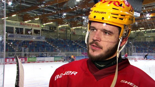 Eishockey-Profi Lukas Kälble von den Fischtown Pinguins steht am Rande der Eisfläche bei einem Interview.