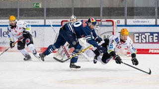 Der Münchner Eishockey-Spieler Andreas Eder verteidigt gegen Jan Urbas von den Fischtown Pinguins Bremerhaven, der dabei aufs Eis stürzt.