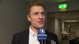 Eishockey-Coach Alexander Sulzer von den Fischtown Pinguins steht in einem Gang in der Kölner Eisarena beim Interview nach dem ersten Play-off-Sieg.
