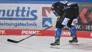 Eishockey-Profi Christian Wejse steht nach einer Nasenverletzung vorne übergebeugt auf dem Eis, Blutstropfen sind auf dem Eis zu sehen.