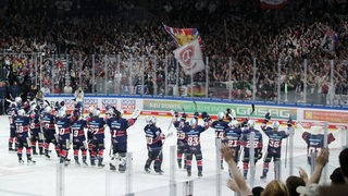 Eishockey-Spieler der Eisbären Berlin stehen nebeneinander auf dem Eis und lassen sich von der Fans auf den Rängen für den Finaleinzug feiern.