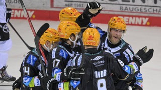 Eishockey-Spieler der Fischtown Pinguins kommen auf dem Eis zusammen, um mit Nicholas Jensen seinen Treffer gegen Köln zu bejubeln.