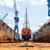 Ein rotes Schiff liegt auf dem Trockenen in einem Dock.