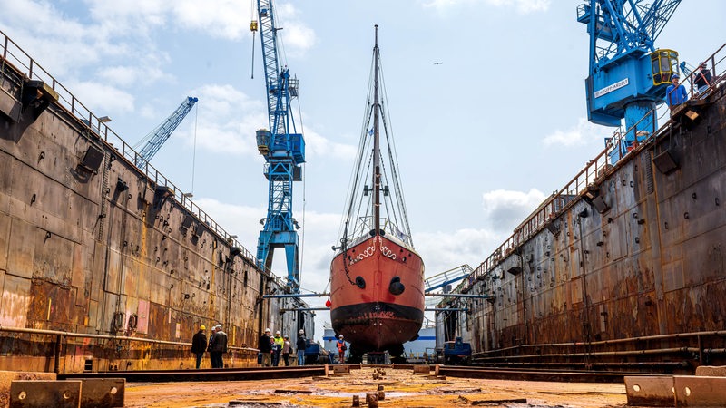 Ein rotes Schiff liegt auf dem Trockenen in einem Dock.