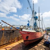 Ein rotes Schiff liegt auf dem Trockenen in einem Dock.