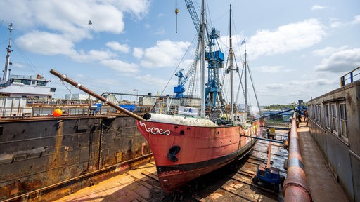 Ein rotes Schiff liegt auf dem Trockenen in einem Dock.