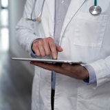 Ein Arzt hält ein Tablet in der Hand.