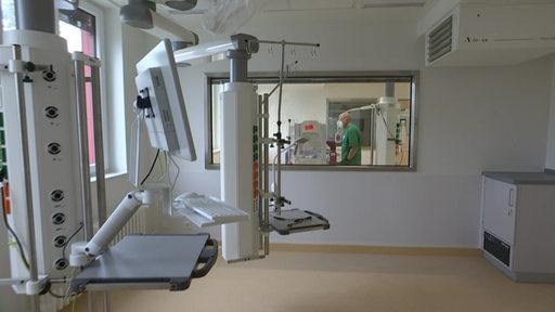 Ein Mann in grünem Kittel steht in einem Behandlungszimmer eines neuen und noch leeren Kinderkrankenhauses.