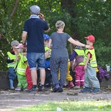 Eine Kindergruppe mit Betreuerin und Betreuer macht einen Ausflug in einen Park.