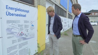 Der Investor Klaus Meier und der Geschäftsführer Johannes Aderholz stehen vor dem Plan des Energiekonzept Überseeinsel. 