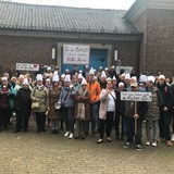 Eine Personengruppe protestiert für den Erhalt der Kita-Küchen, einige haben Plakate, Kochlöffel oder Kochmützen dabei