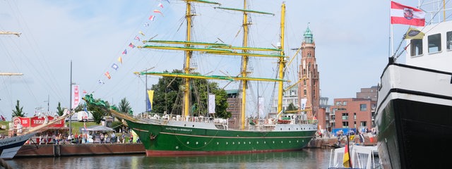 Ein grünes Segelschiff liegt im Hafen.