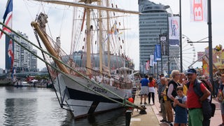 Mehrere Perosnen stehen neben einem Schiff.