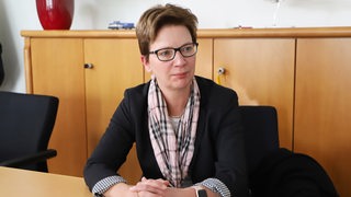 Justizsenatorin Claudia Schilling sitzt in ihrem Büro und blickt nachdenklich.