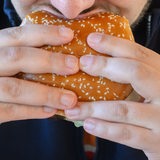 Nahaufnahme: Ein Mann beißt in einen Hamburger