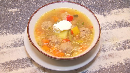 Eine Gemüsesuppe mit Klößen in einem Teller.