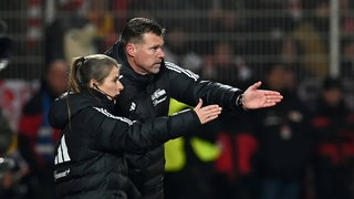 Union-Trainer Grote und Eta gestikulieren am Spielfeldrand.