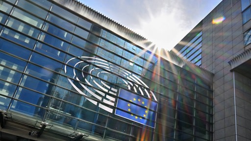 Fassade des Europaparlaments in Brüssel, darüber die gleißende Sonne