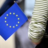 Der Arm einer Person, die eine EU-Flagge hält, ist zu sehen. 
