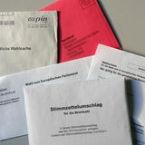 Wahlunterlagen für eine Briefwahl zum Europäischen Parlament liegen auf einem Tisch.