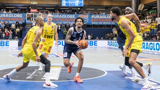 Drei Baskets-Spieler versuchen ihren Gegenspieler von den Syntainics MBC zu stoppen.